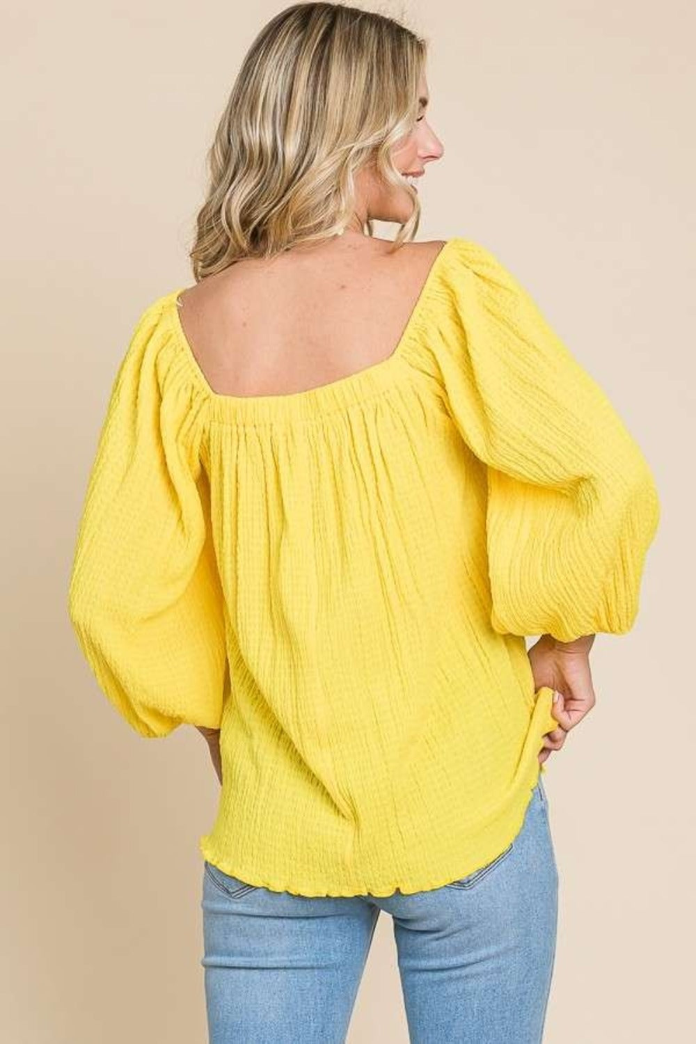 Woman wearing yellow square neck puff sleeve top with fitted waistline and ruched detailing, perfect for casual or dressy occasions.