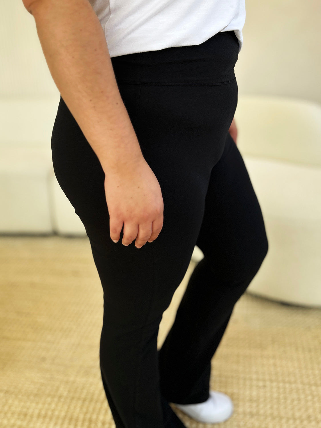 Woman wearing high-waisted wide waistband bootcut active pants in black, highlighting the flattering and comfortable fit.