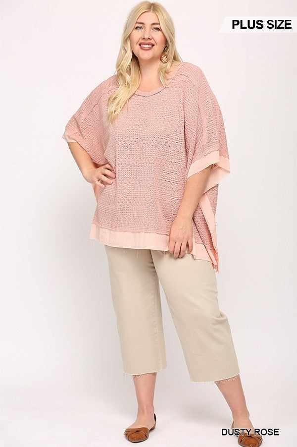 Plus size model in dusty rose light knit and woven boxy top with poncho sleeves, paired with neutral pants.