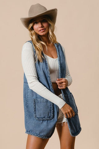 Woman wearing braided trim denim vest with pockets and cowboy hat
