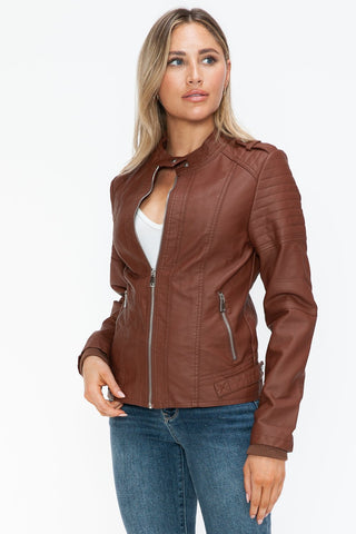 Woman wearing Brandy PU Leather Biker Jacket with side zip pockets, showcasing stylish design and brown pleather material.