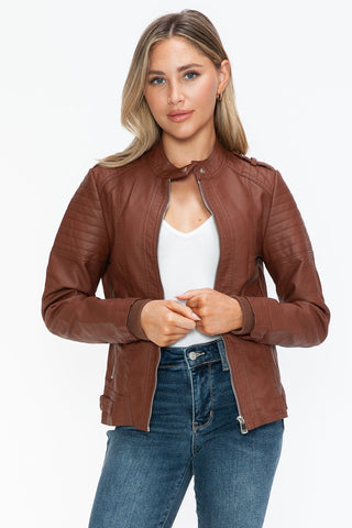 Woman wearing a Brandy PU leather biker jacket with side zip pockets, showcasing basic style in brown pleather.