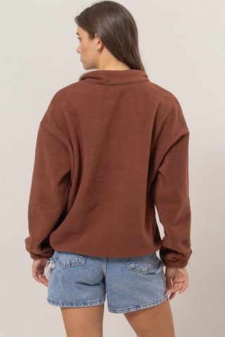 Woman wearing brick fleece color block half zip sweatshirt with casual denim shorts, viewed from the back.