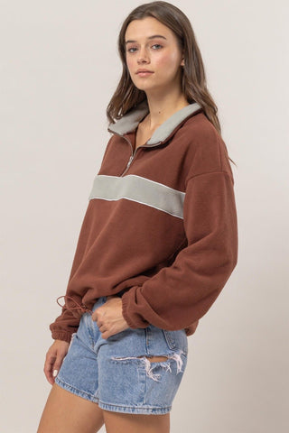 Woman wearing brick fleece color block half zip sweatshirt with denim shorts