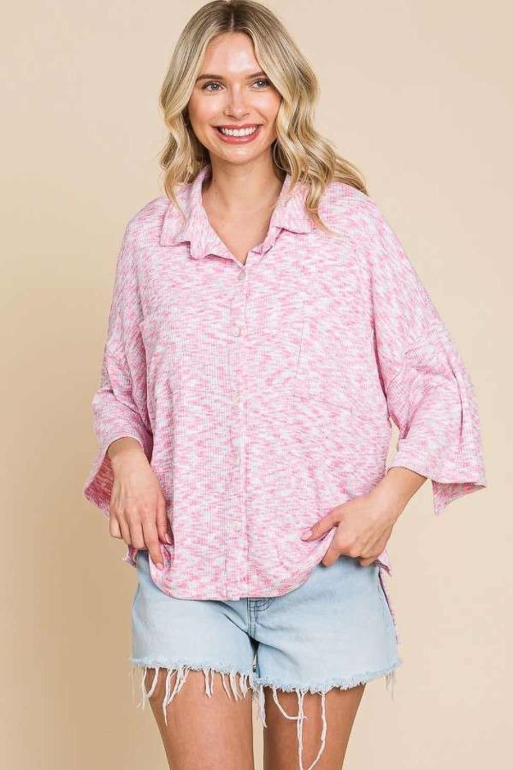 Woman wearing a pink button-up drop shoulder slit shirt with basic style and slightly stretchy fabric, paired with denim shorts.