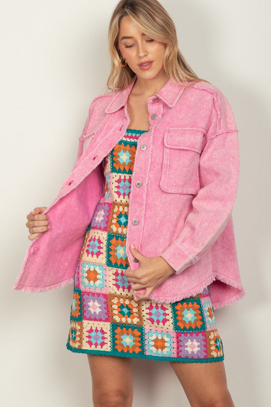 Woman wearing a pink button-up raw hem long sleeve jacket over a colorful geometric dress.