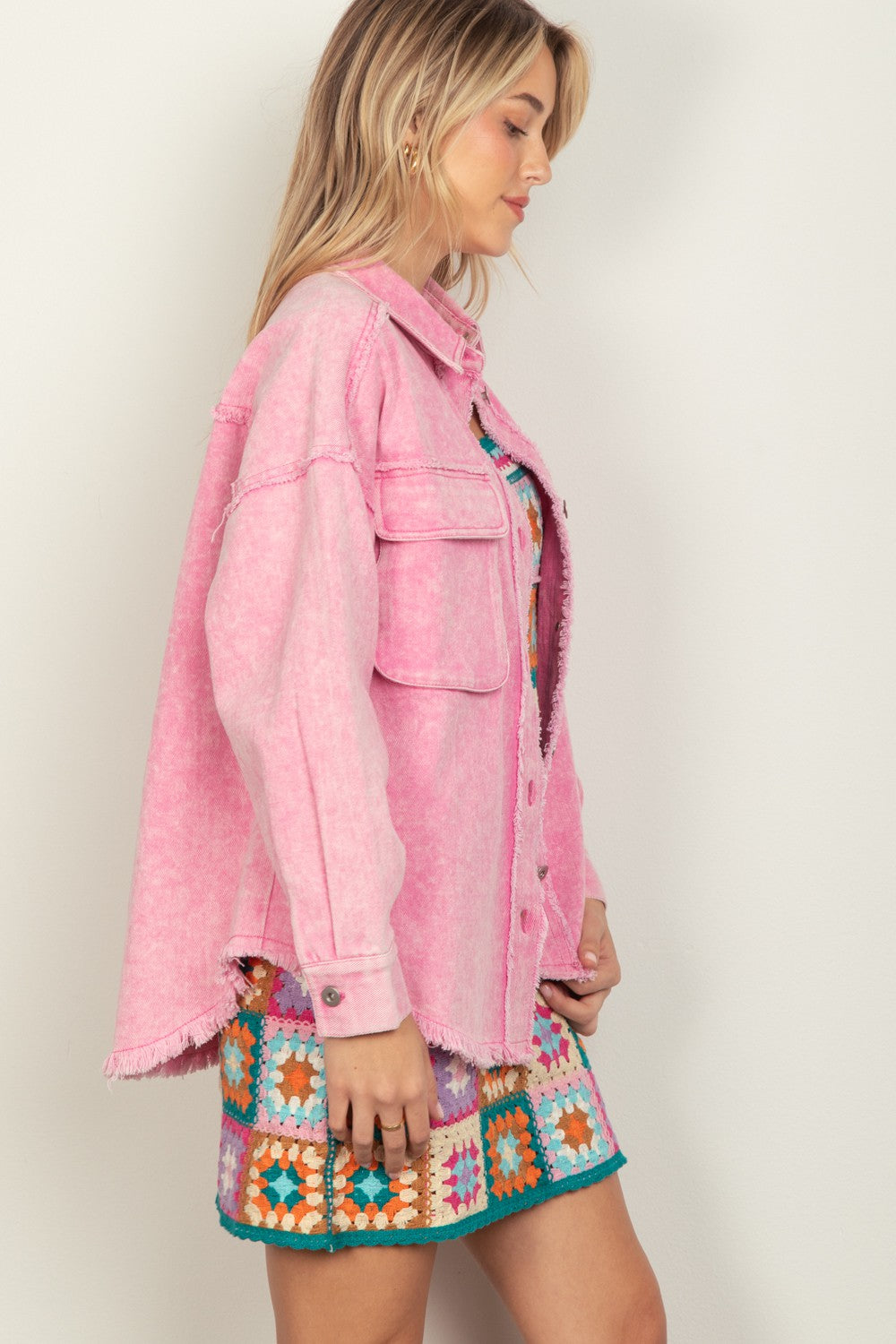 Pink button-up raw hem long sleeve jacket styled over a colorful dress, featuring a basic design with unlined rayon and spandex blend.