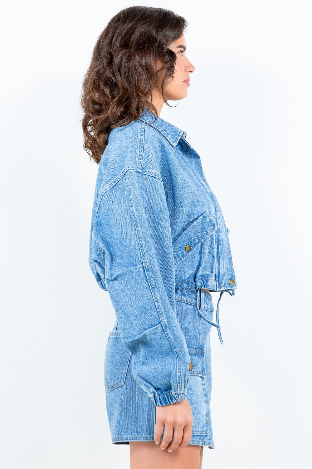 Woman wearing American Bazi drawstring waist crop denim jacket with elastic banded hem and cuffs, featuring a trendy cropped length.