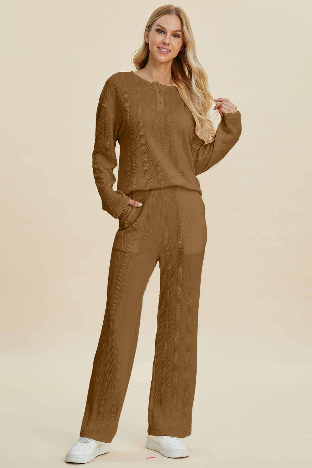 Woman wearing brown cable-knit long sleeve top and pants set with button details, slightly stretchy fabric, made of polyester and spandex.