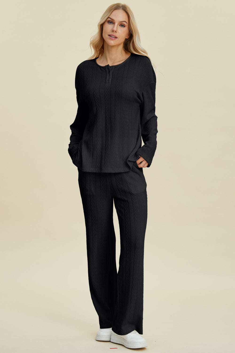 Woman wearing a cable-knit long sleeve top and pants set, buttoned two-piece with slight stretch, made of polyester and spandex.