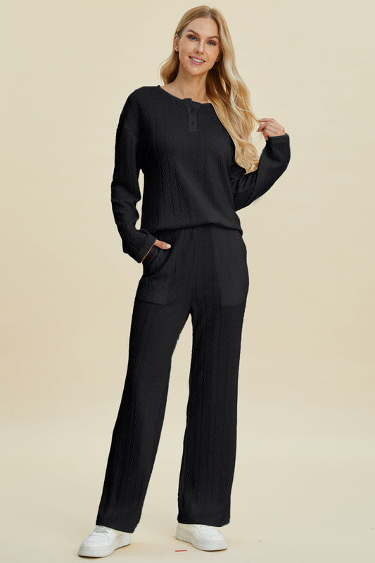 Woman wearing a black cable-knit long sleeve top and pants set, with button details and slightly stretchy fabric.