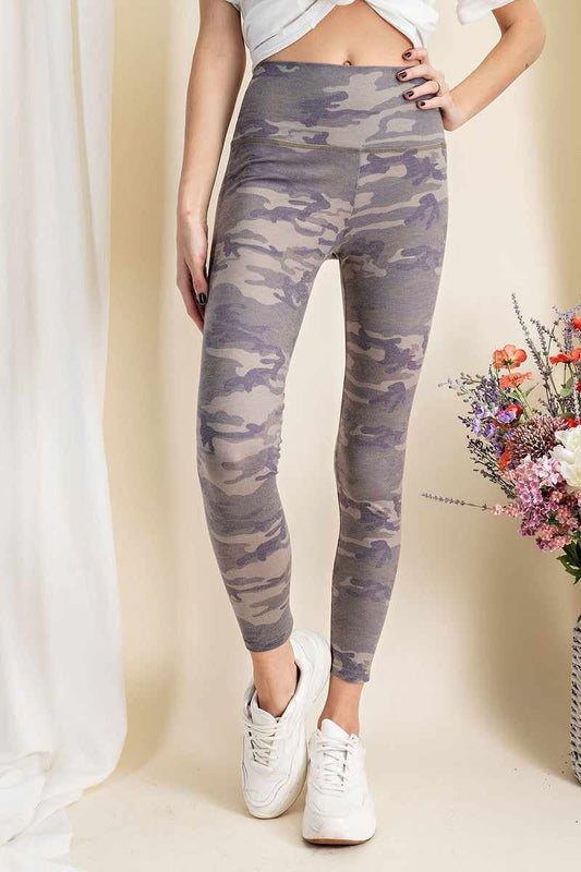 Woman wearing olive camouflage-printed rayon spandex leggings with a mid-rise fit, paired with white sneakers and a casual top.