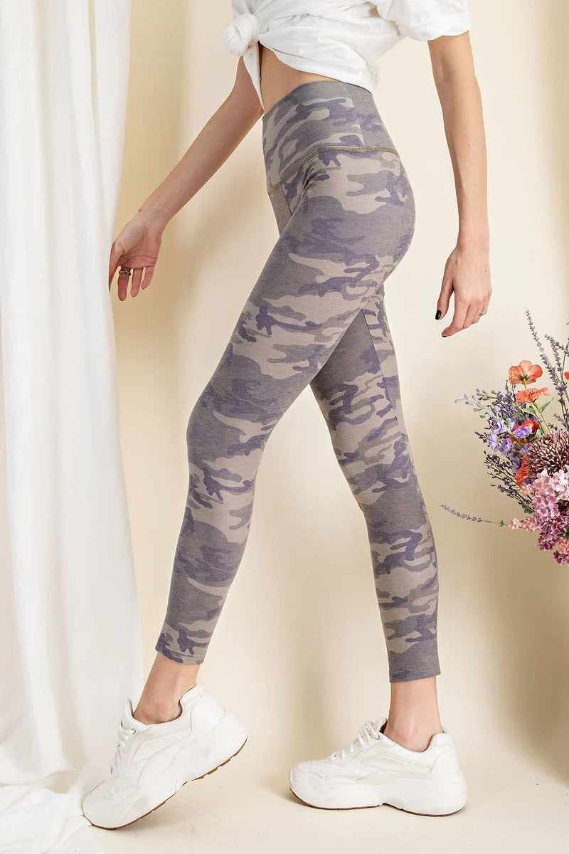 Olive camouflage-printed rayon spandex leggings on model, showcasing buttery-soft texture and mid-rise fit with white sneakers.