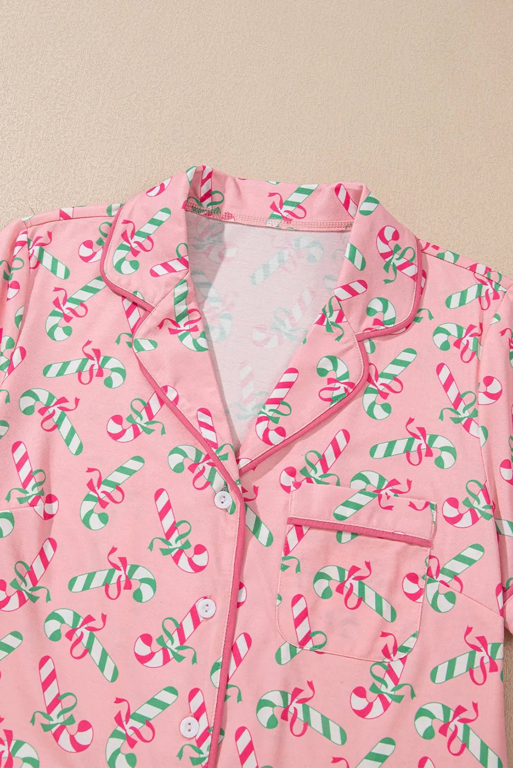 Pink candy cane collared neck pajama top with green and red festive design.