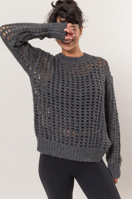 Woman wearing a grey openwork knit cover up with round neck and long sleeves, showcasing chic layering fashion.