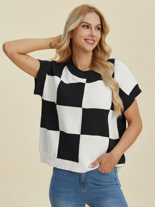 Woman wearing black and white checkered round neck short sleeve sweater, slightly stretchy, made from viscose, polyester, and polyamide.