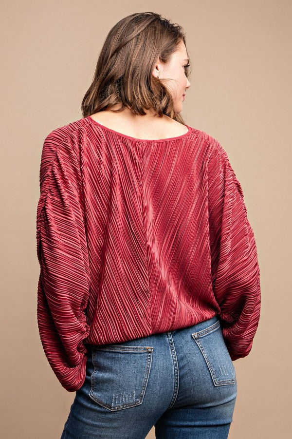 Burgundy satin pleated top with drawstring and snap buttons, back view, paired with jeans, showcasing elegant style and texture.