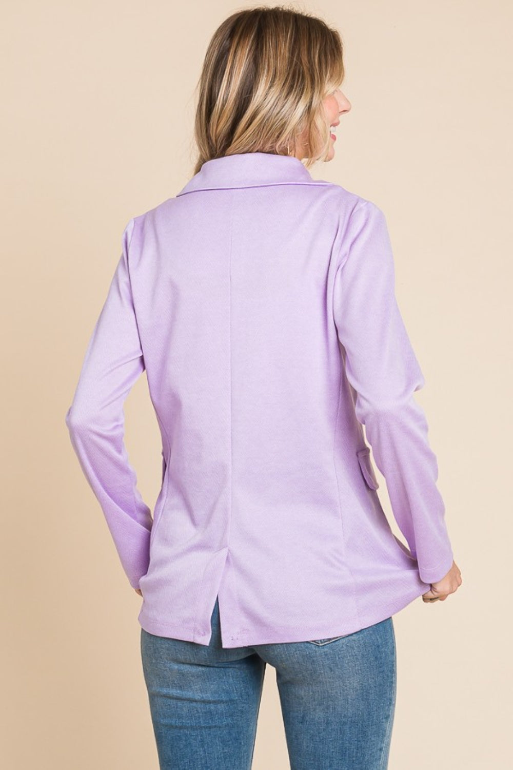 Woman wearing a lilac button-up long sleeve slit blazer made of polyester and spandex, showcasing its sleek back design.