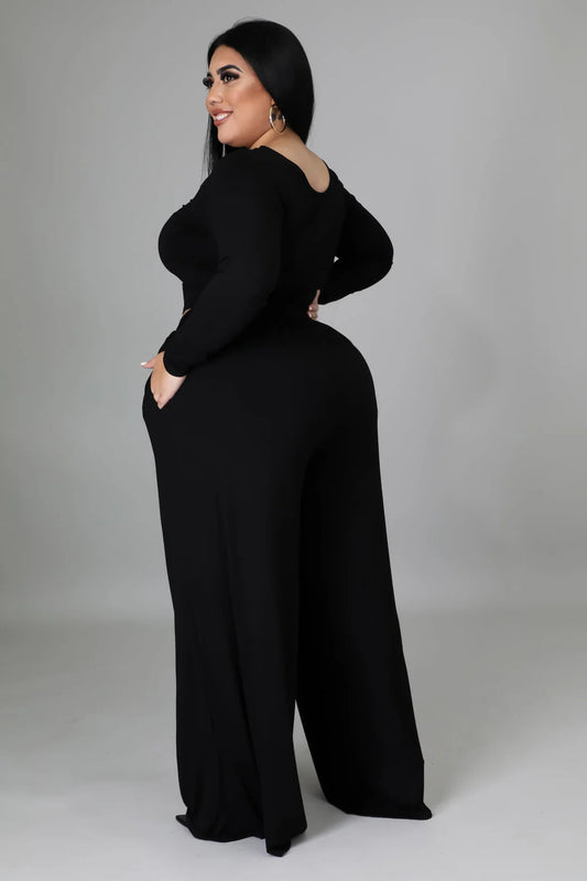 Woman in chic black long sleeve crop top and loose pants set, showcasing a stylish silhouette with square neckline and convenient pockets.