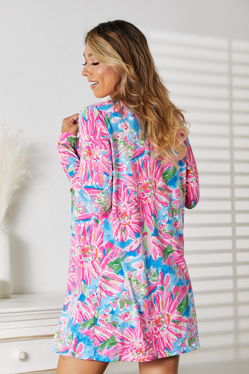 Woman wearing a colorful floral open front long sleeve cardigan, showcasing vibrant spring style.