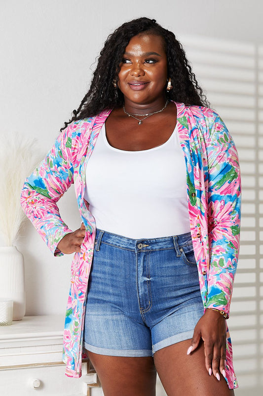 Woman wearing floral open front long sleeve cardigan with denim shorts, showcasing versatile and stylish layering piece.