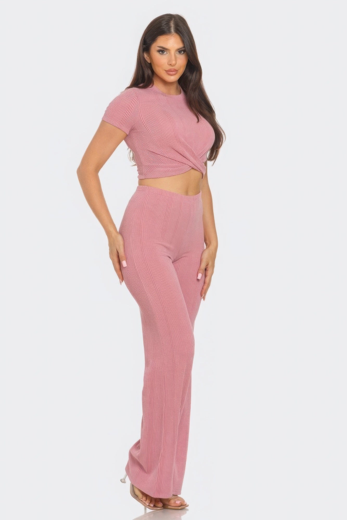 Woman wearing a pink front twist detail crop top and high-waisted flare pants set, made from rib knit fabric, perfect for a chic look.