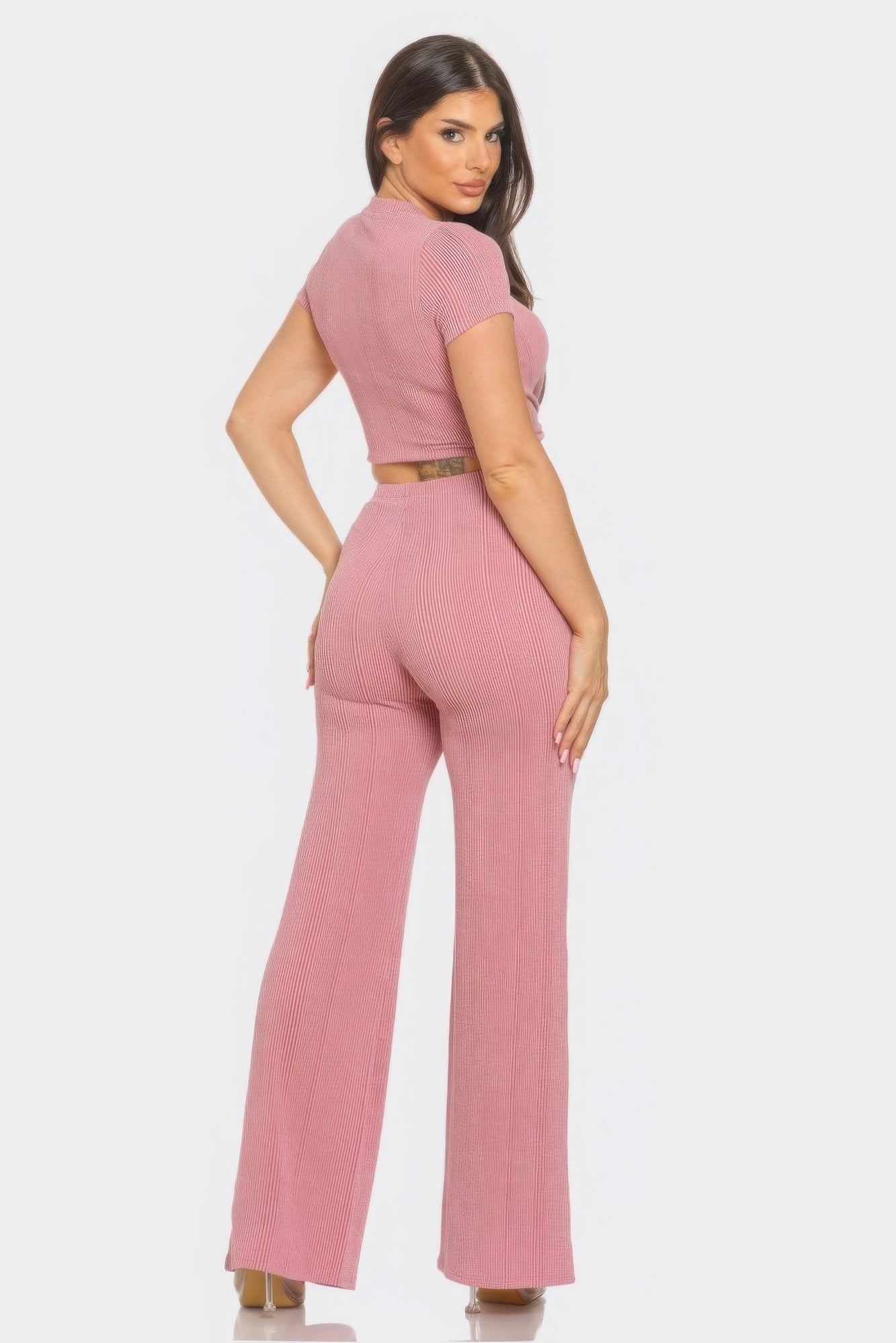 Woman wearing pink front twist detail crop top and flare pants set, showcasing retro-inspired style with flattering silhouette.