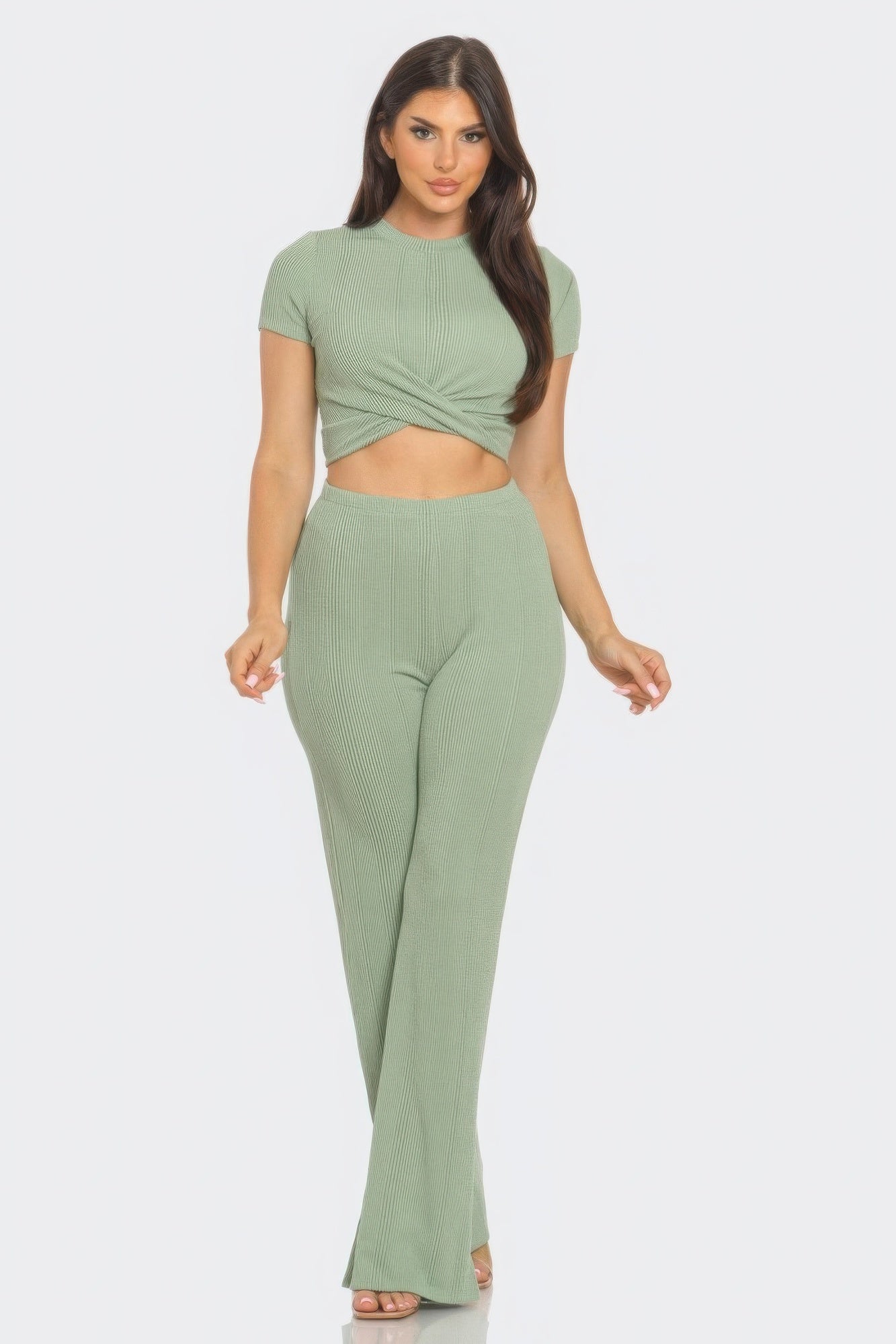 Woman wearing a chic front twist crop top and flare pants set in a soft green, perfect for a stylish night out or daytime look.