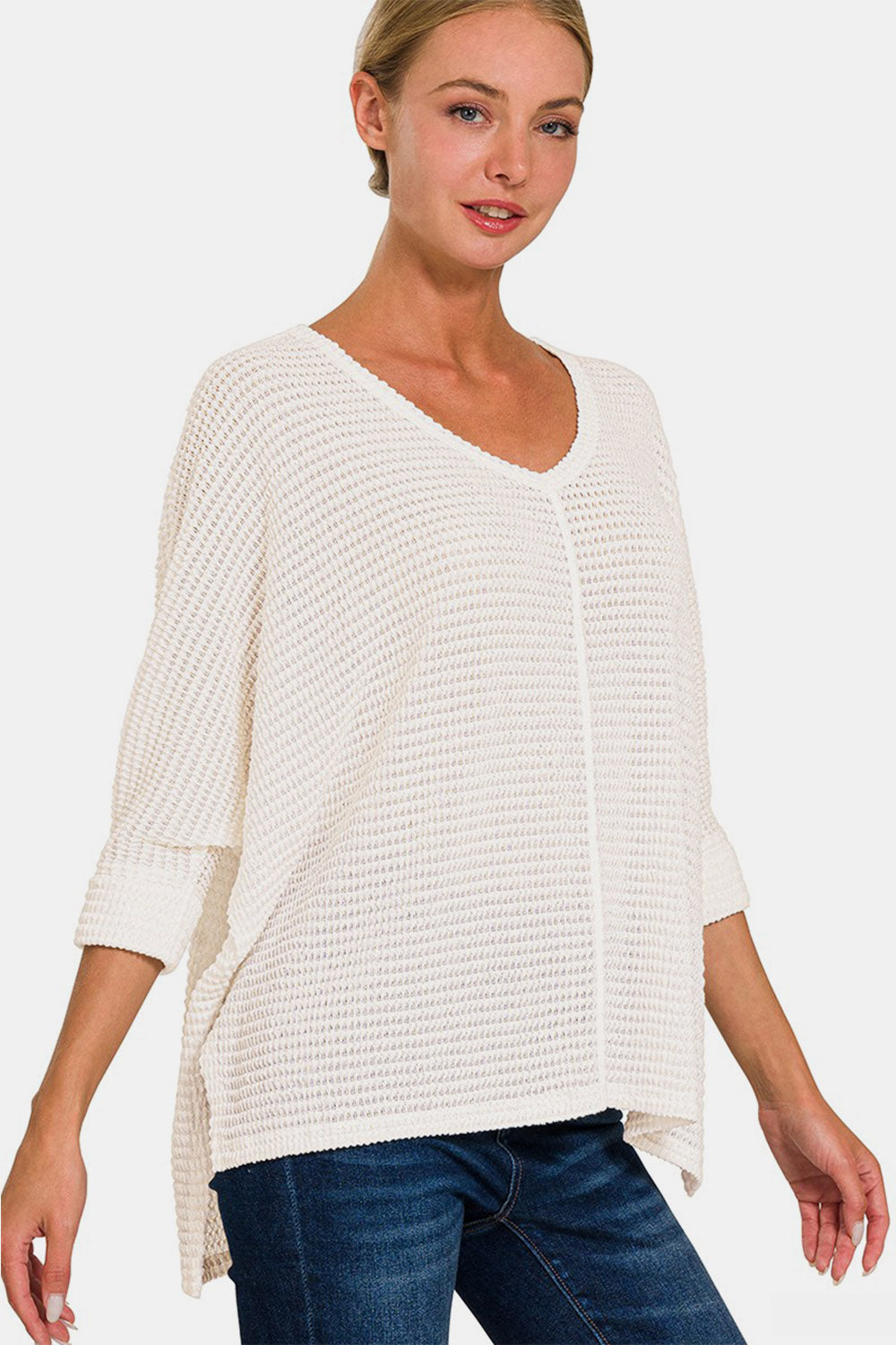 Woman wearing full size round neck high-low slit knit top in white, paired with jeans. Fashionable, versatile, cozy knit fabric.