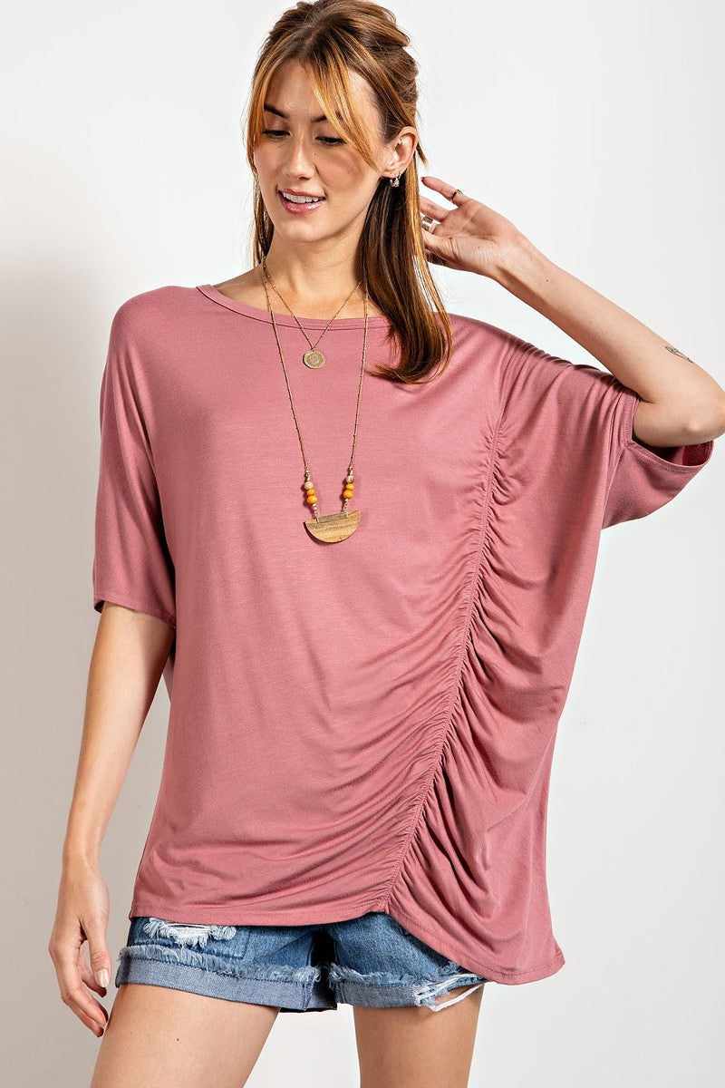 Mauve loose fit top with ruched side detailing and boat neckline, styled with denim shorts.