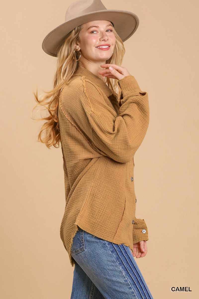 Woman wearing camel mineral wash button down top with high low hem and blue jeans.