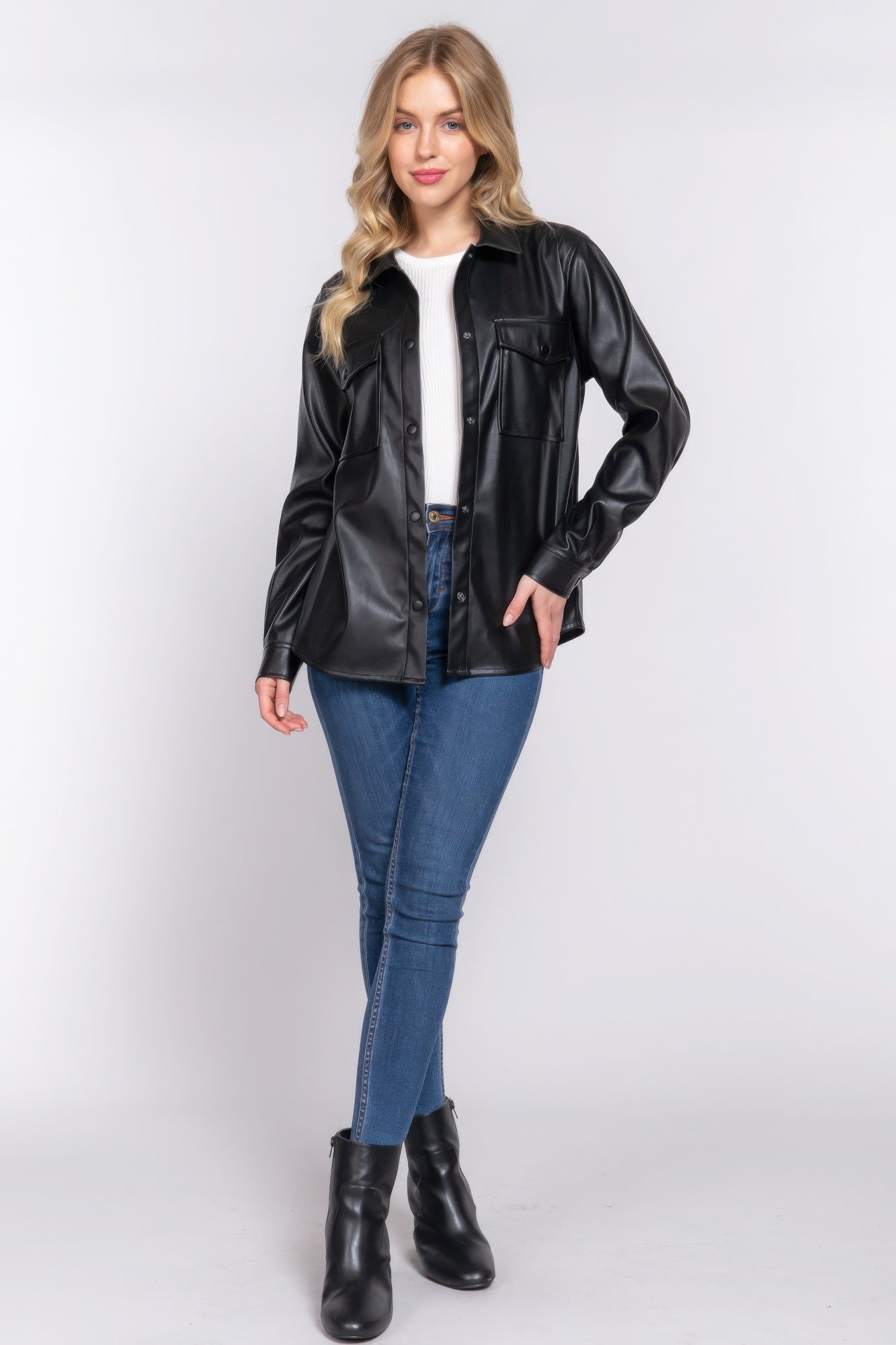 Woman wearing long sleeve faux leather shacket in black with jeans and boots, ideal for stylish layering and seasonal transitions.