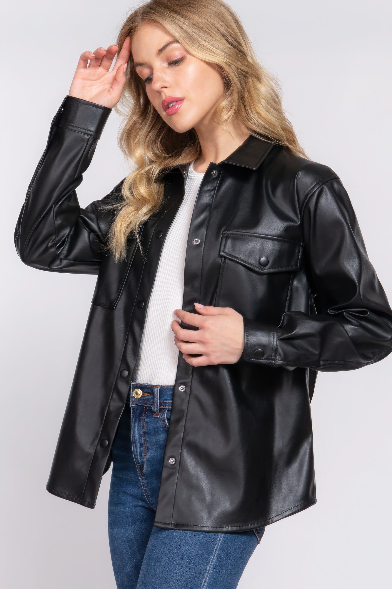 Woman wearing a black long sleeve faux leather shacket with jeans, showcasing a chic and versatile fashion choice.