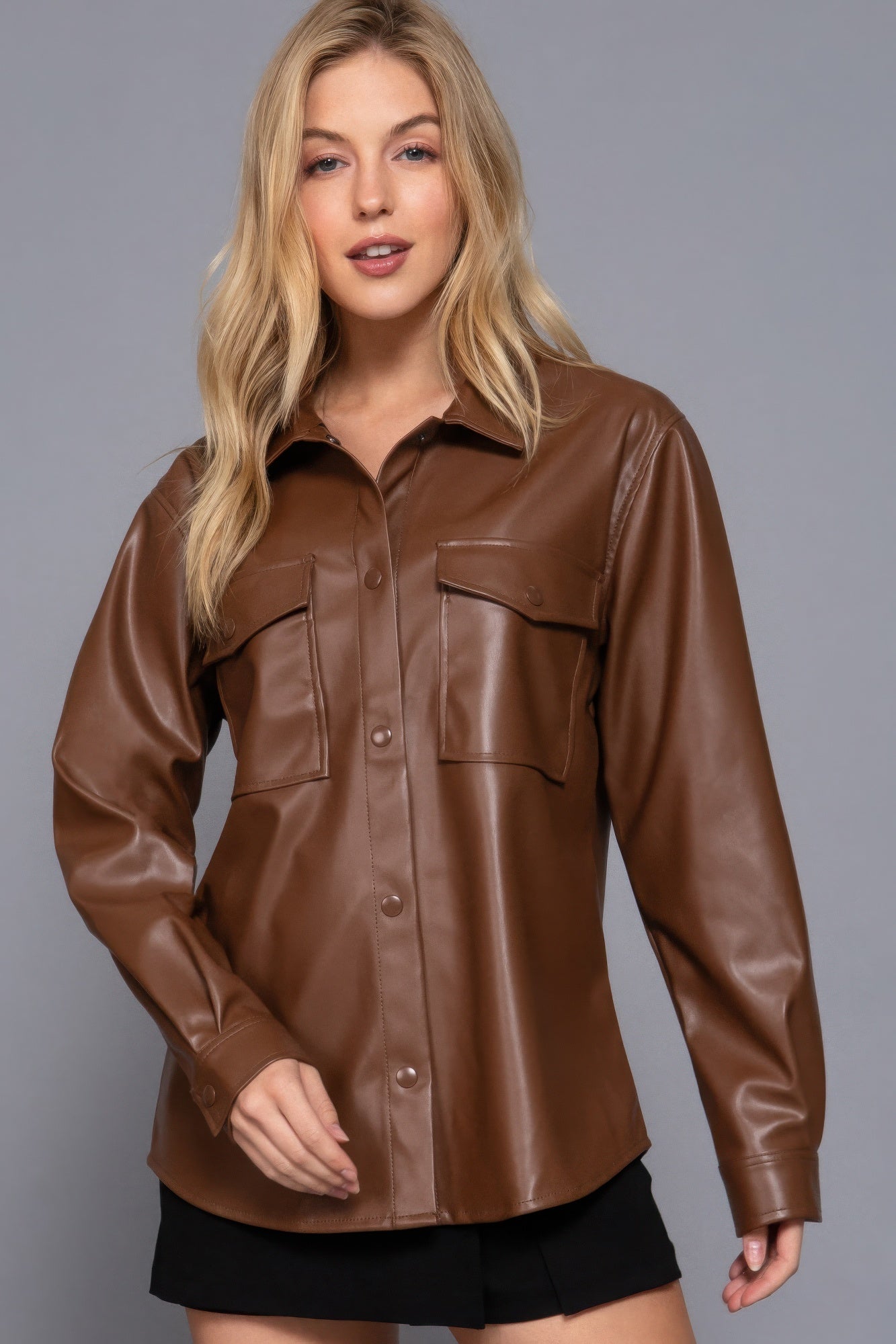 Woman wearing chic brown faux leather shacket, long sleeves, button-up, perfect for layering, versatile fashion style.