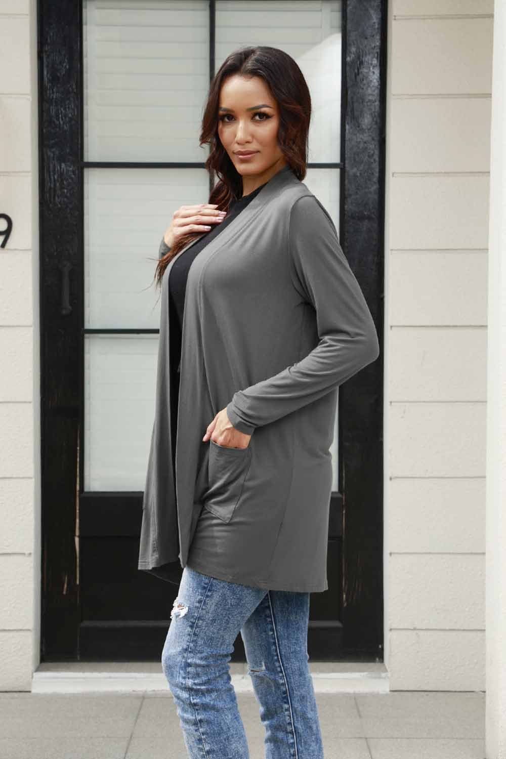 Woman wearing open front long sleeve cardigan with pockets, stylish thin design, perfect for layering, gray color, polyester material.