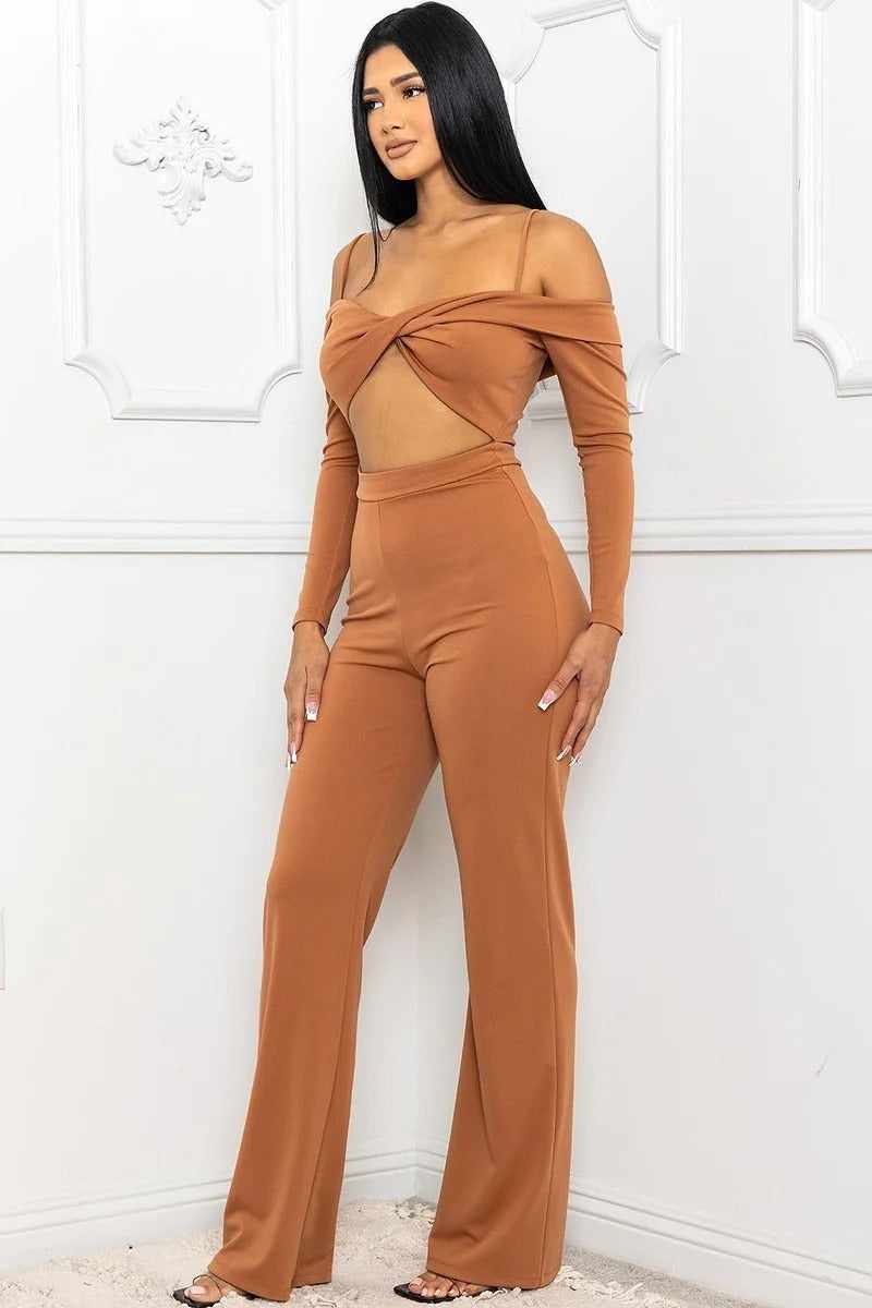 Cinnamon open shoulder jumpsuit with cutout detail, spaghetti straps, twist on bust, long sleeves, and bell bottoms.