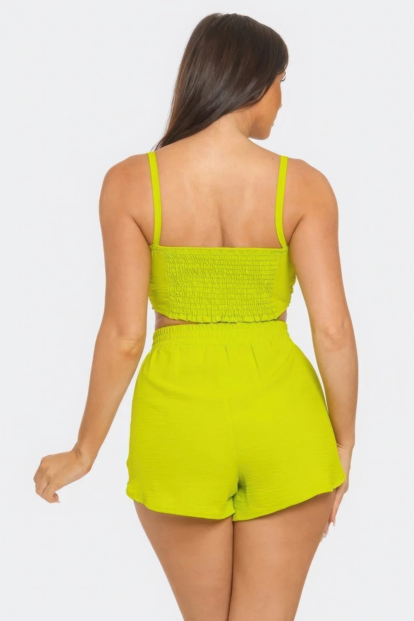 Woman in lime green shorts set with smocked back and elastic waistband, showcasing comfortable and stylish summer outfit.