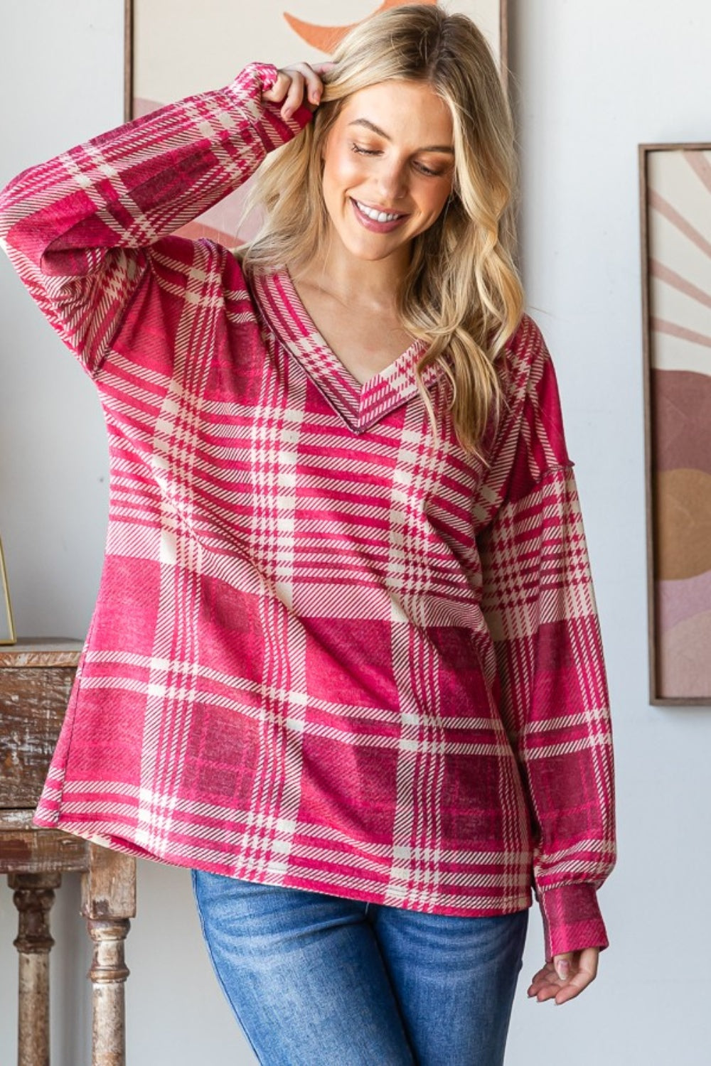 Woman wearing a pink plaid drop shoulder V-neck T-shirt with relaxed fit and exposed seam detailing.