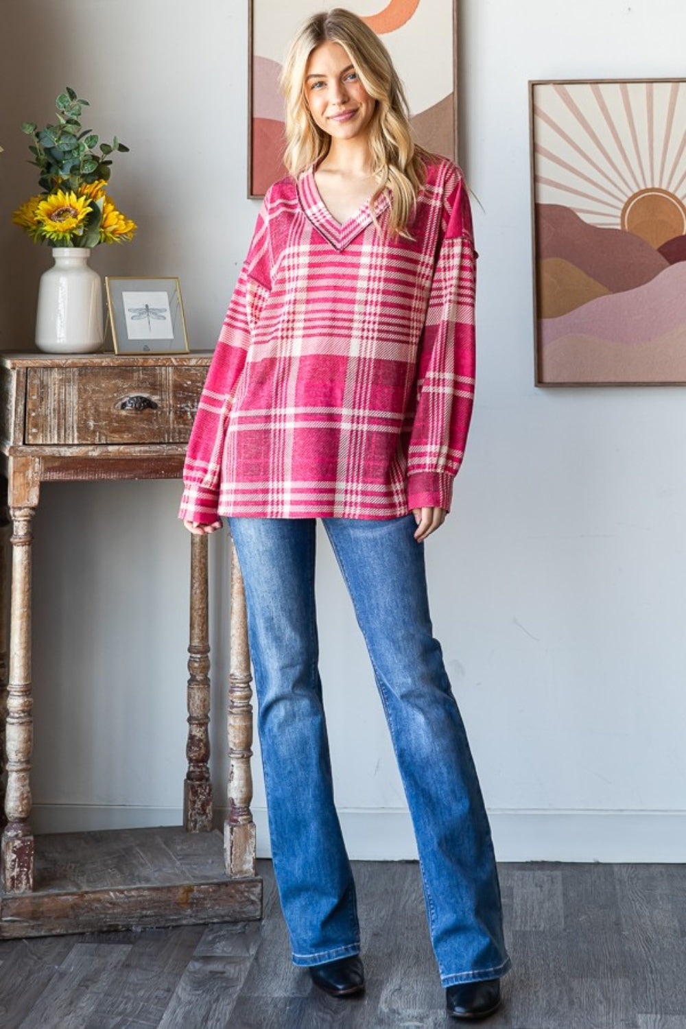 Woman wearing plaid drop shoulder V-neck T-shirt with relaxed fit and exposed seams, paired with jeans for a chic, casual look.