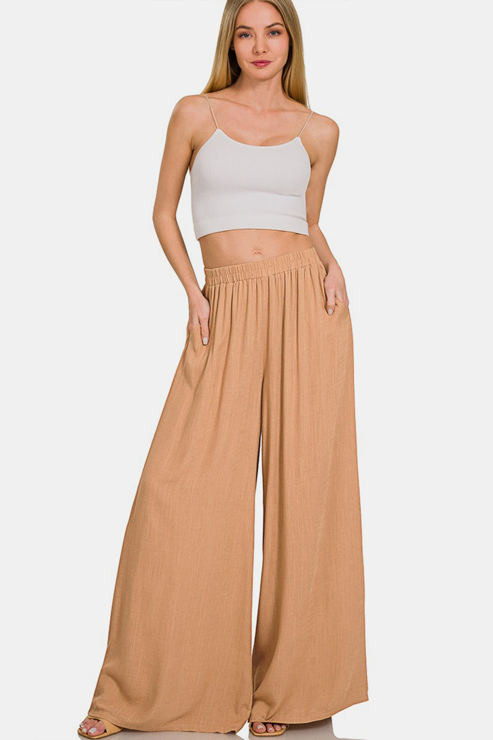 Woman wearing pleated linen blend wide leg pants with a basic style, composed of 25% linen and 75% rayon.