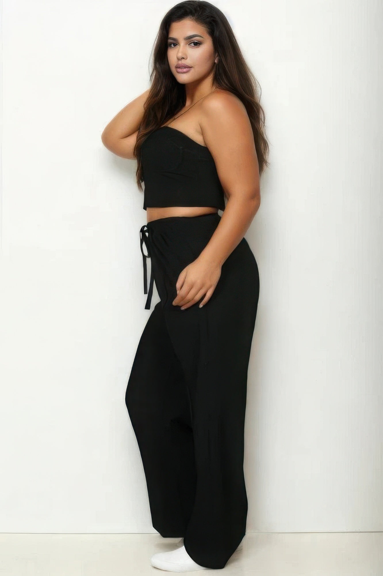 Woman wearing a stylish black bustier crop cami top and slant pocket straight pants set, showcasing chic and sophisticated fashion.