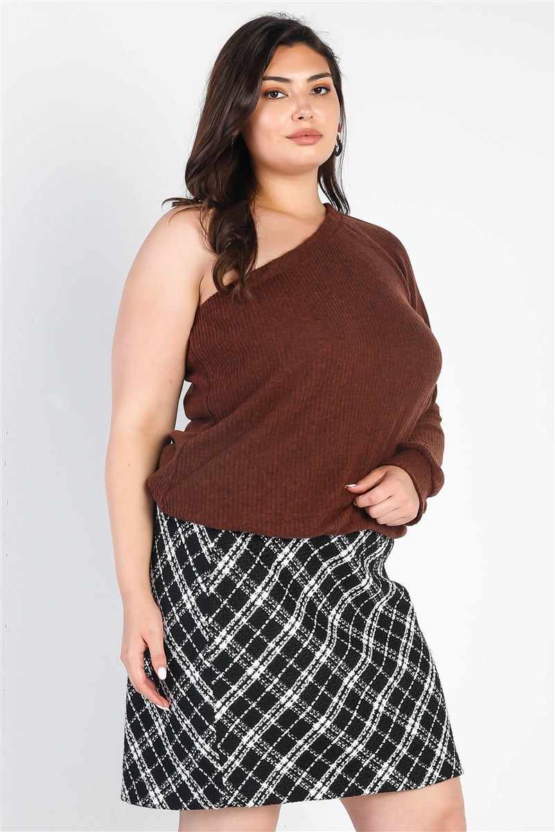 Plus size model wearing a brown ribbed one shoulder top with cuffed long sleeve, styled with a black and white plaid skirt.