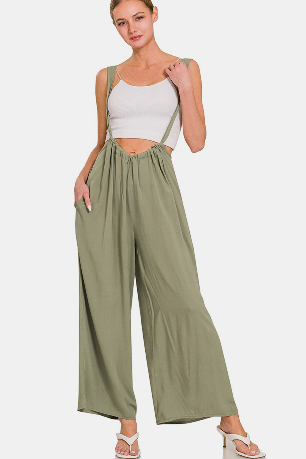 Woman wearing stylish green wide leg overalls with pockets and wide straps, perfect for a chic and comfortable outfit.