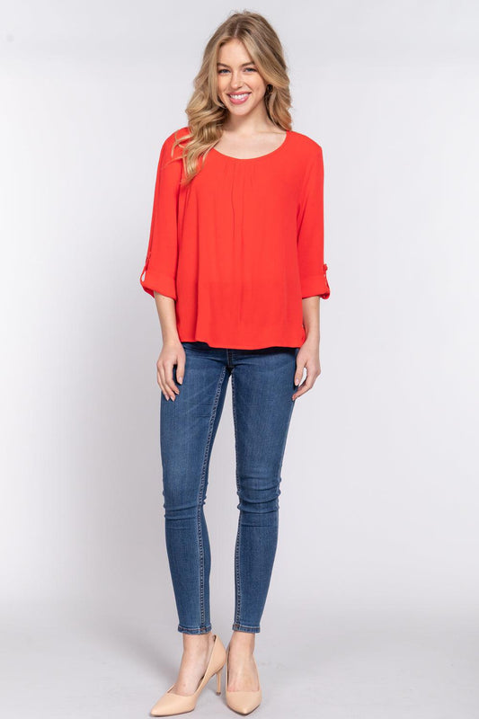 Woman wearing tomato red roll up sleeve pleated blouse and jeans, featuring a round neck and 3/4 sleeves, made of 100% rayon.