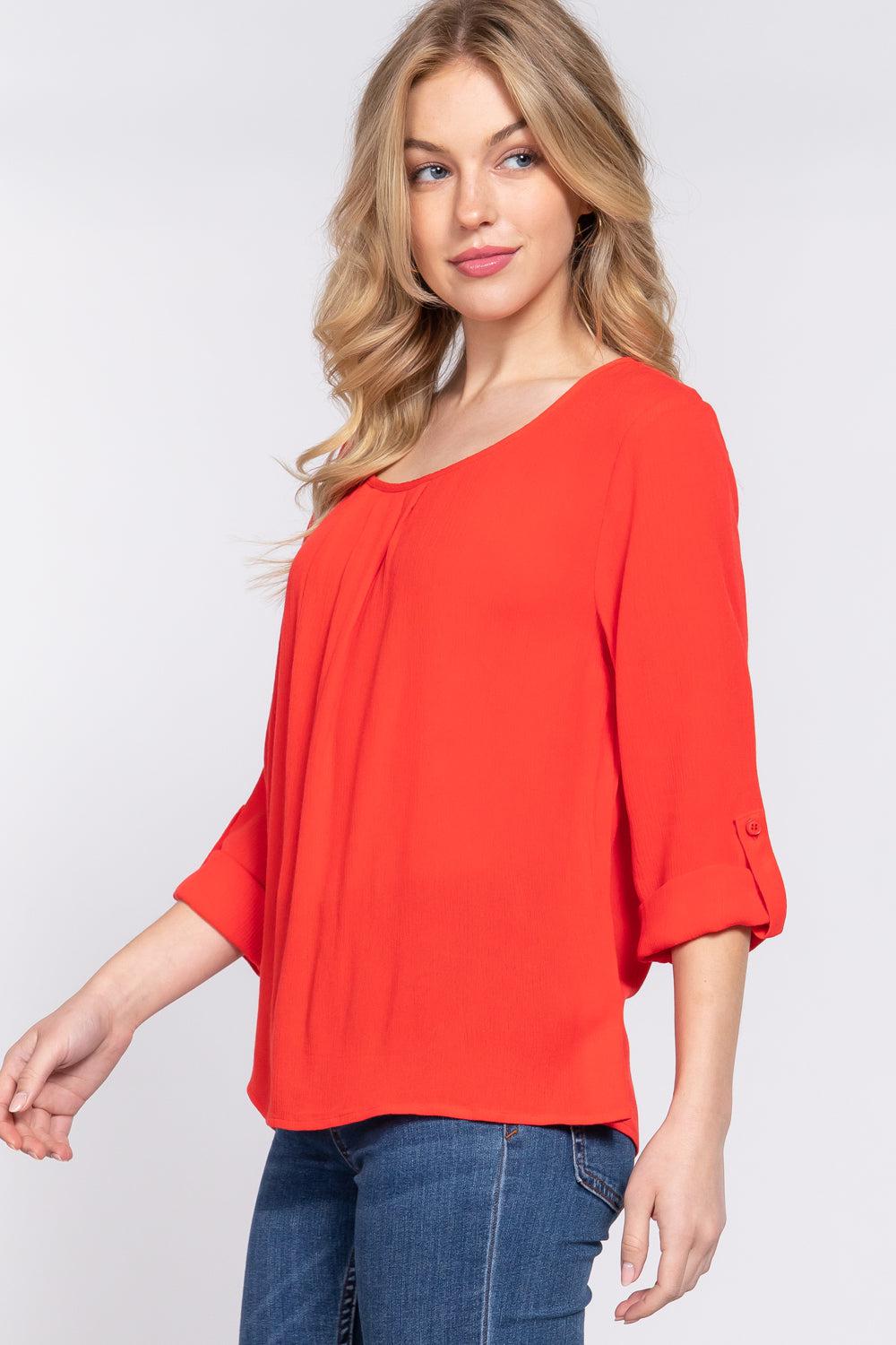 Woman wearing a tomato-colored roll-up sleeve pleated blouse with round neck and 3/4 sleeves, paired with jeans.