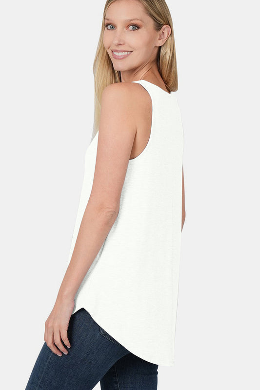 Woman wearing a chic round neck curved hem tank top in white, paired with jeans, showcasing its flattering silhouette and versatile style.