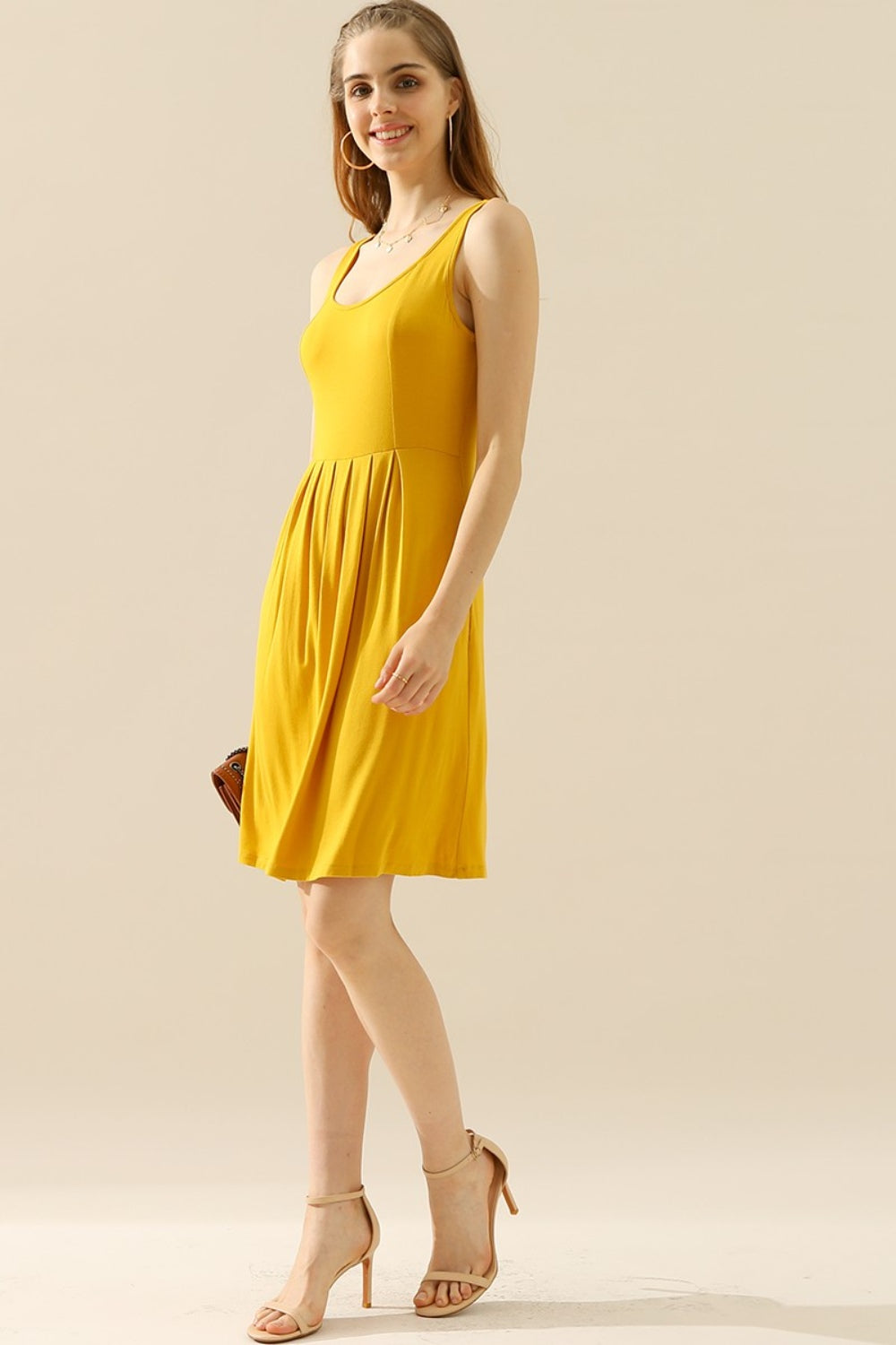 Woman wearing a yellow round neck ruched sleeveless dress with pockets, showcasing its basic style and high stretch fabric.