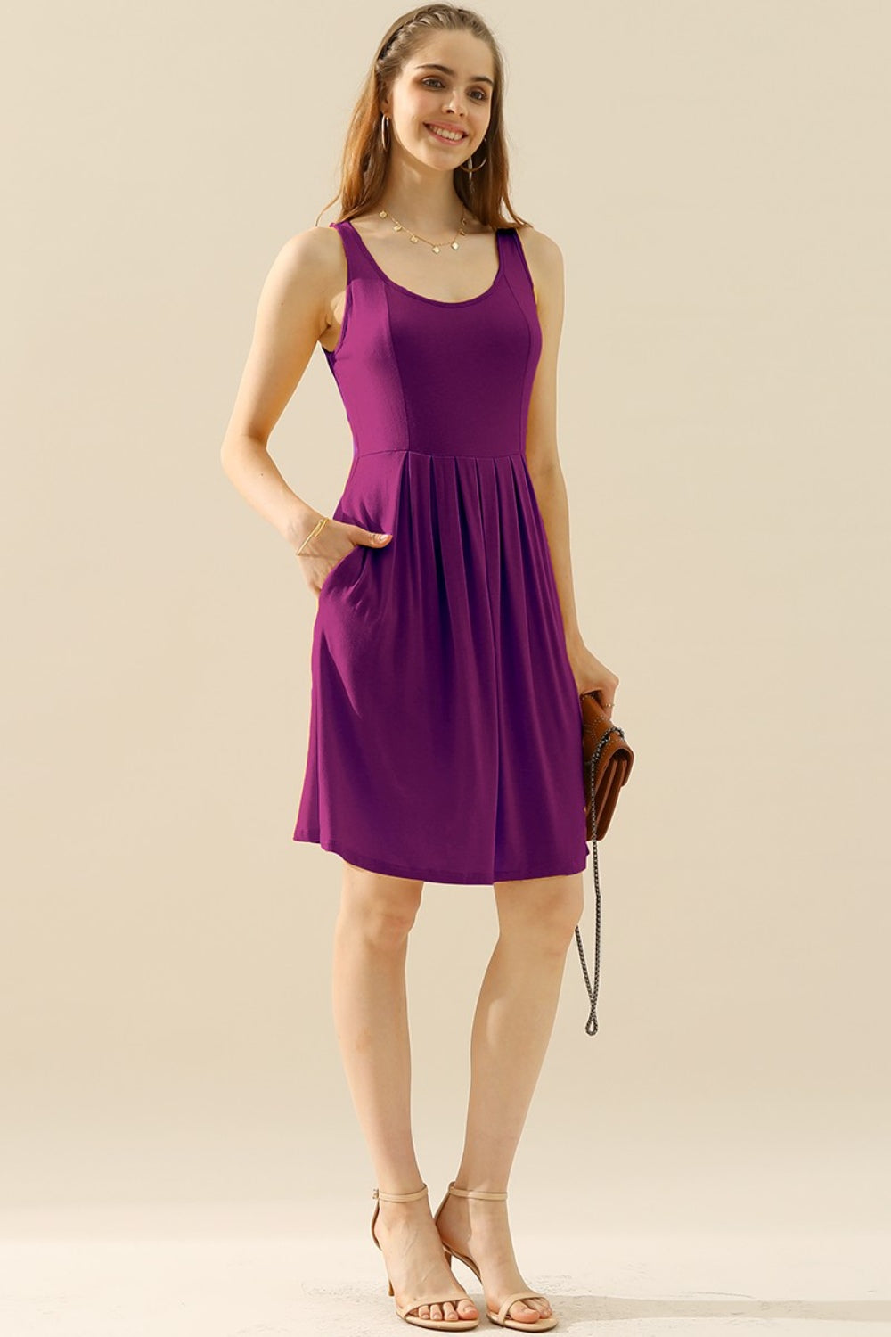 Woman wearing a purple round neck ruched sleeveless dress with pockets, showcasing a stylish and comfortable fit.