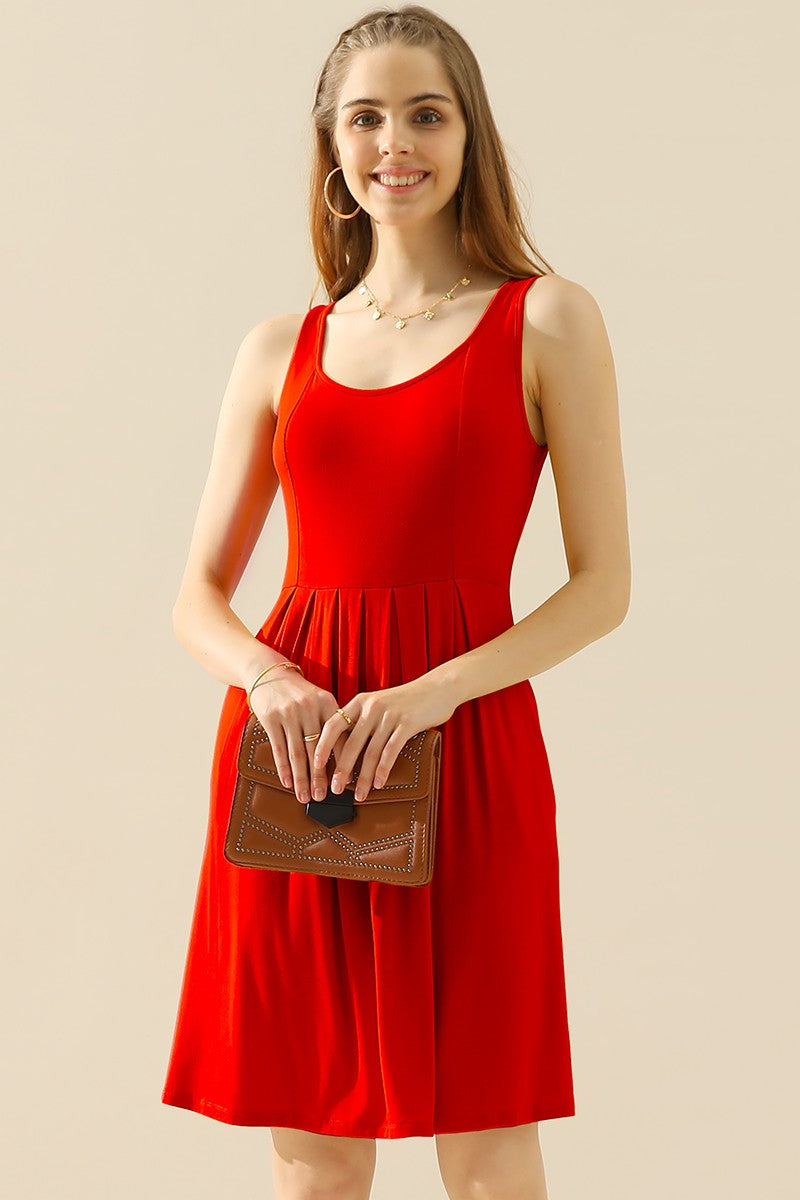 Woman wearing a red sleeveless round neck ruched dress with pockets, holding a brown clutch.