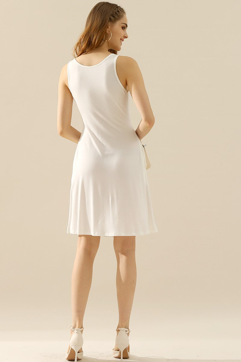 Woman wearing a white round neck ruched sleeveless dress with pockets, showcasing the back view in a minimalist setting.